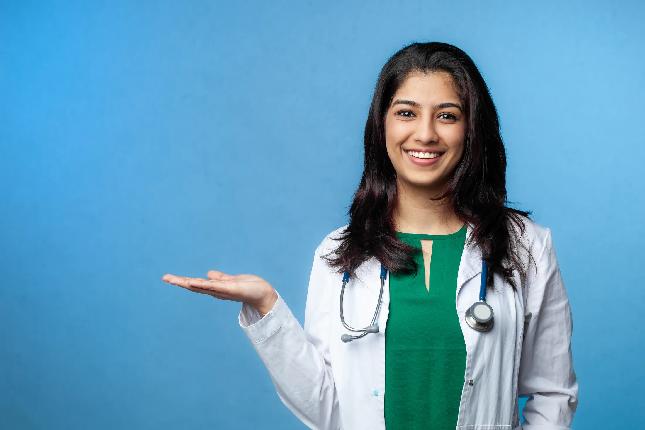 beautiful-young-doctor-lady-pointing-with-hand-copy-space-studio-shot-isolated-blue-background